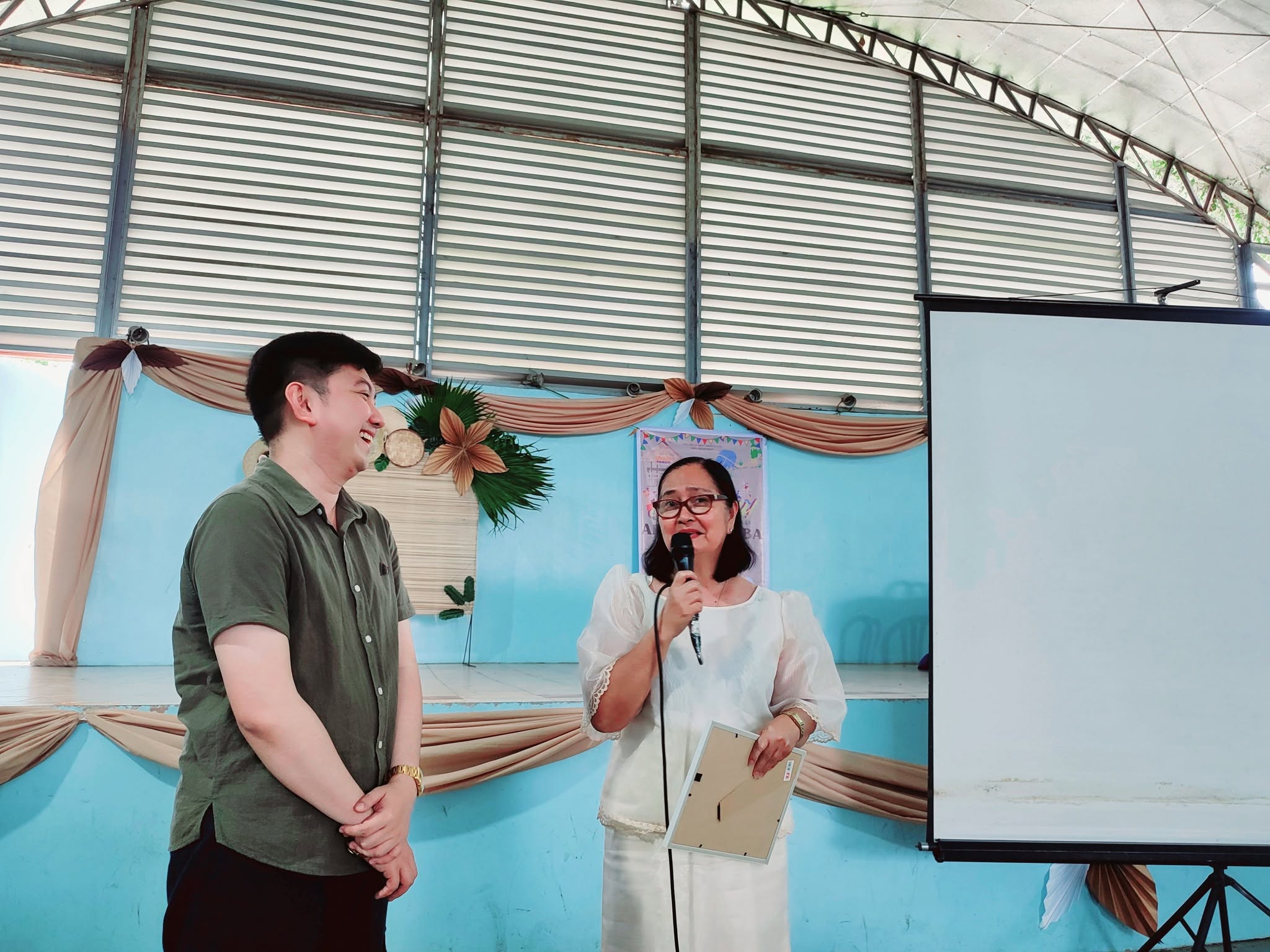 Jayson being recognized by a College of Mary Immaculate faculty member holding a framed certificate
