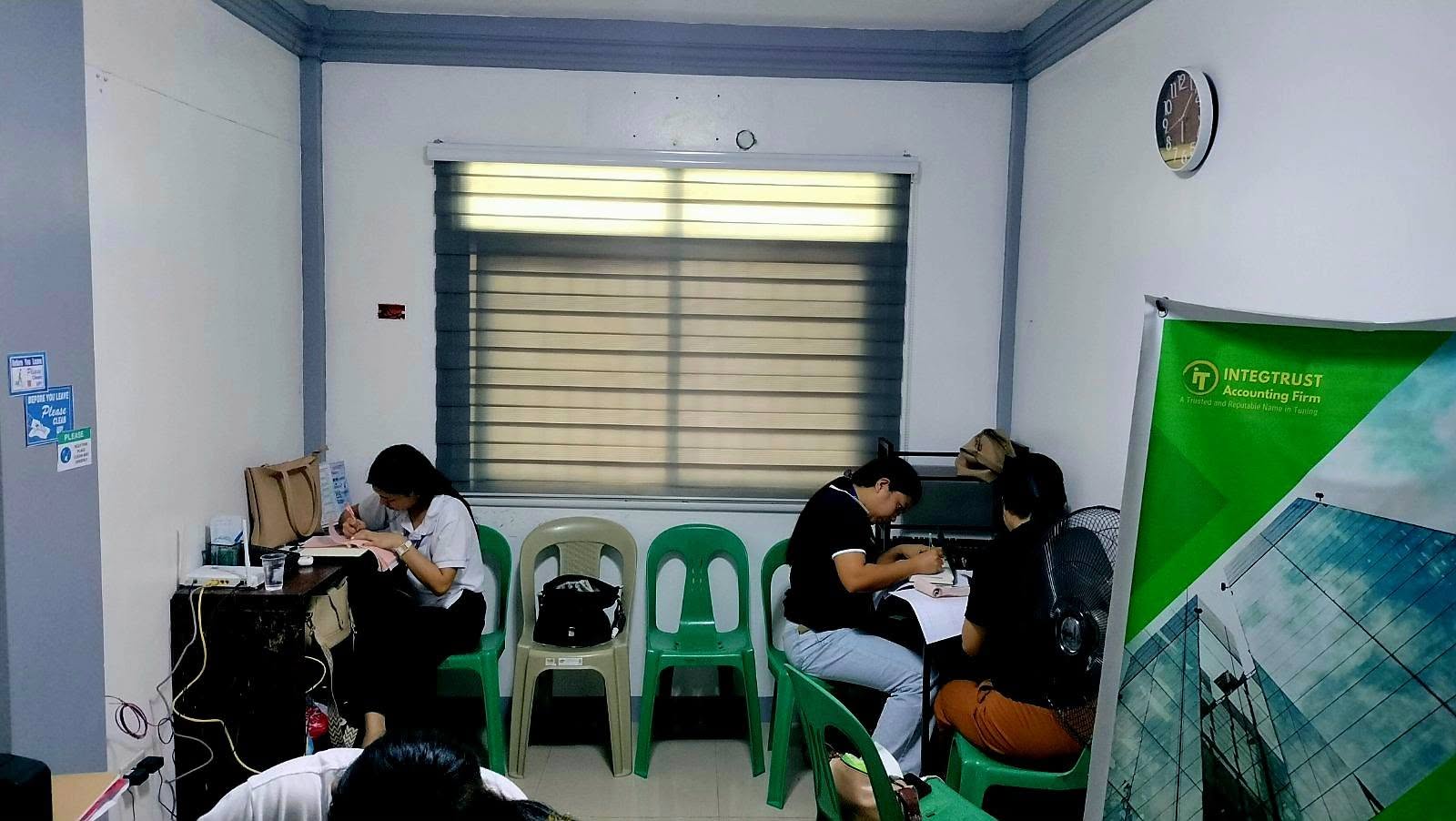 Business administration students writing at desks during a bookkeeping workshop at the IntegTrust Accounting Firm office
